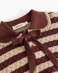 A close-up of a knit polo shirt by MatMar, featuring horizontal stripes in deep burgundy and cream with a matching burgundy bow tie at the collar.
