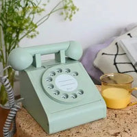 Vintage green telephone on a cork table with a cup of tea and decorative elements.