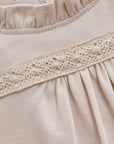 Close-up of beige fabric with lace trim and '3M' label.