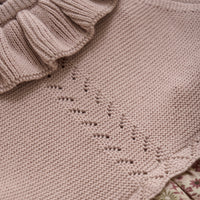 Close-up of a knitted garment with a subtle pattern on beige fabric.