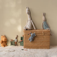 Wicker basket with plush toys on a light-colored floor against a beige wall