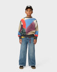 Child wearing a colorful sweater and jeans on a white background