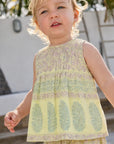 Child wearing a patterned sleeveless top and pants outdoors