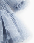 Close-up of a light blue tulle skirt with polka dots on a white background