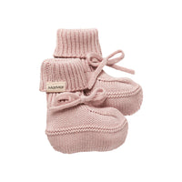 Pair of pink knitted baby booties with a brand label on a white background