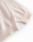 Close-up of a light pink knitted sweater on a white background