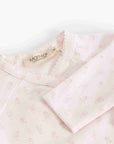 A close-up of a baby long-sleeve top by Marni, featuring a pale pink and white micro-floral pattern, a scalloped neckline, and a visible brand label.