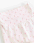 A close-up of a light pink fabric garment, likely a baby romper or bodysuit, featuring a delicate repeating pattern of small pink flowers and leaves.