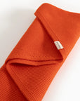 Orange knitted sweater with a brand label on a light background