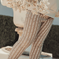 Person wearing patterned pants holding dried flowers outdoors