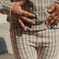 Person wearing a plaid shirt and pants with a blurred background