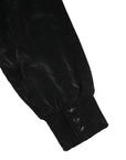 Close-up of a black velvet garment with buttons on a white background
