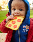 Child holding a toy pizza in a park