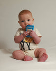 Baby sitting on a white surface holding a blue container.