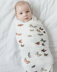 Baby wrapped in a butterfly-patterned swaddle on a white blanket