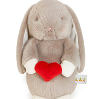 Plush toy rabbit holding a red heart on a white background