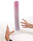 Colorful cylindrical object held by two hands against a white background