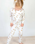 Child wearing a white outfit with gold animal prints on a plain background