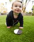 Baby crawling on grass with a rock in front