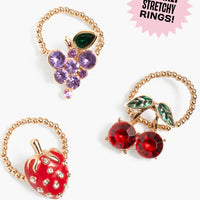 Three sparkly stretchy rings with fruit designs on a white background