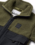 Close-up of a fleece zip jacket by Molo, featuring an olive green sherpa collar and chest patch with a black logo, combined with a black lower body and cargo pocket.