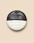 Round wall light fixture with black and white marbled design on a beige background