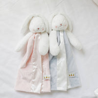 Two plush bunny toys with pink and gray blankets on a white background