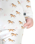 Children's onesie with horse pattern held by a hand