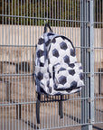 Backpack with soccer ball pattern hanging on a metal fence