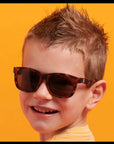 Child wearing sunglasses with a bright orange background