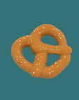 A novelty pretzel-shaped dog toy in a warm brownish-orange color with white faux-seed details, set against a solid teal background.