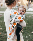 Two children in a park, one holding the other, with a focus on their clothing.