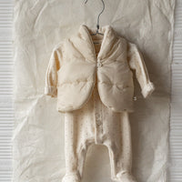 Baby outfit on a hanger against a textured white wall