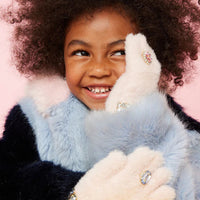 Child holding a fluffy white toy against a pink background
