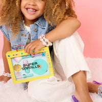 Child holding a toy with 'Super Smalls' branding against a pink background