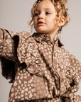 Child wearing a brown patterned outfit against a plain background