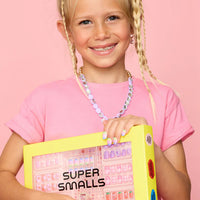 Young girl holding a box labeled 'Super Smalls' against a pink background