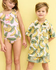 Two children wearing banana-themed clothing on a yellow background