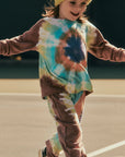 Child wearing a tie-dye shirt and pants on a basketball court