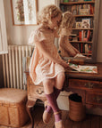 Two young girls in a vintage room with books and a mirror.
