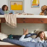 Children playing on a wooden bunk bed in a room with colorful artwork on the wall.
