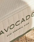 Close-up of a product with 'Avocado Eco Organic Kids' branding on a textured surface.