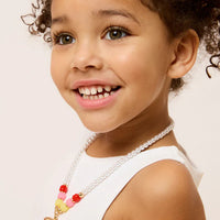 Young girl wearing a necklace with a strawberry pendant on a light background