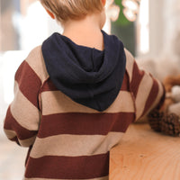 Child wearing a striped sweater with a hood, standing indoors.