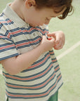 Child wearing a striped polo shirt on a light green background