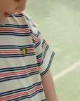 Child wearing a striped shirt with a small logo on a green background