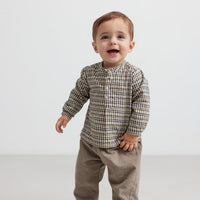 Child wearing a plaid shirt and beige pants on a white background