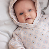 Baby wearing a floral patterned outfit lying on a soft surface