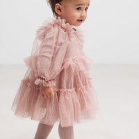 Child wearing a pink tulle dress on a white background