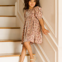 Young girl in a floral dress standing on a staircase